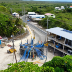 **Nauru's Internet Infrastructure**: "An aerial view of Nauru showcasing new fiber optic cables being installed, with a focus on modern technology juxtaposed against the island's natural beauty. Include elements of digital connectivity like Wi-Fi signals and people using devices in a community setting."